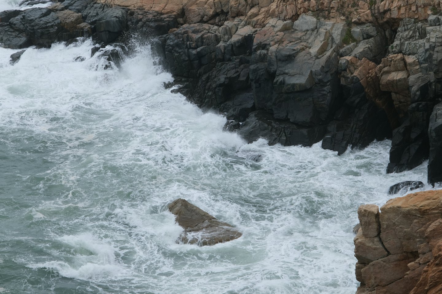 Ocean waves crash against the jagged rocky coastline.