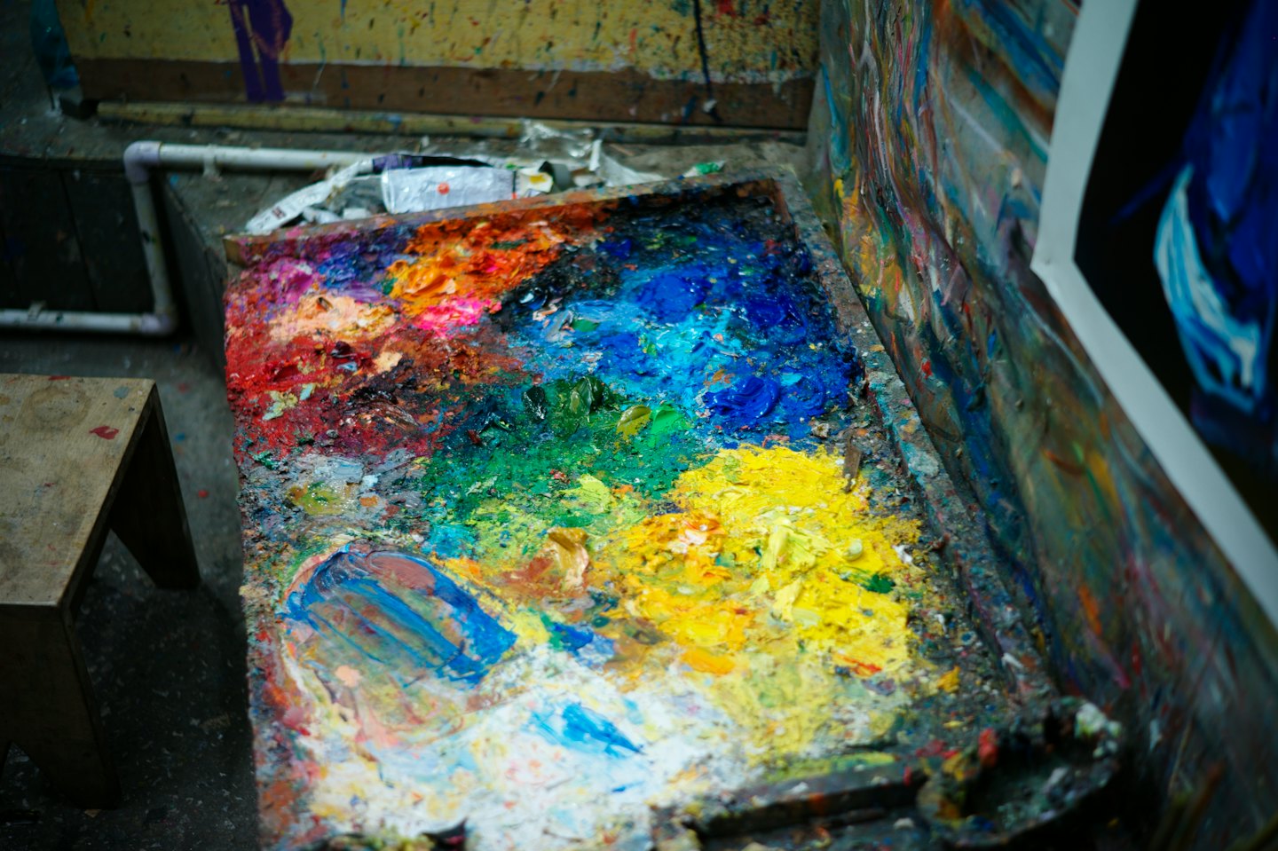 Artist's wooden palette covered in thick, colorful paints.