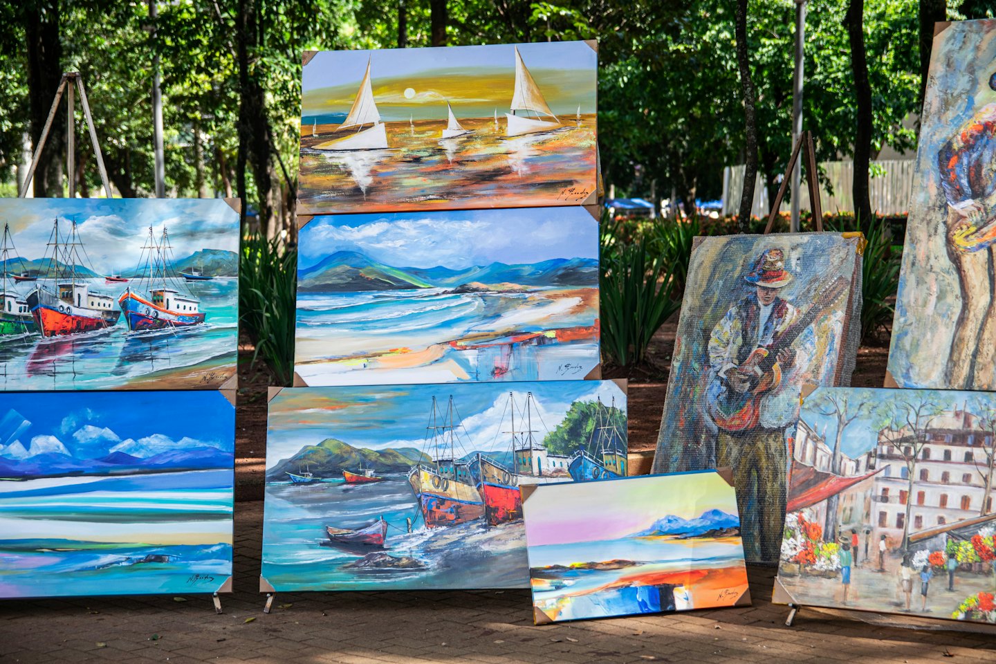 Colorful acrylic paintings displayed outdoors on easels.