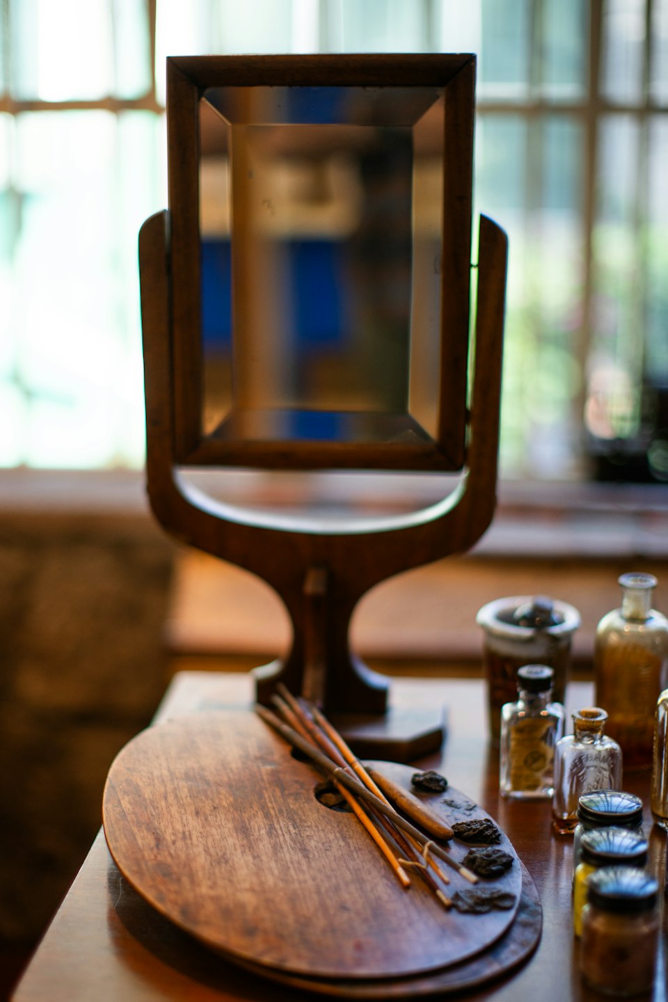 Paintbrushes and a palette rest on a wooden studio table.